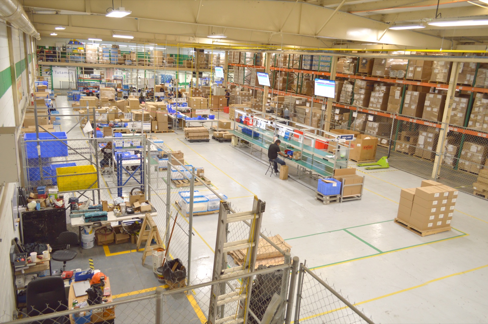 Tutamen Tijuana — assembly floor with workstations, racking, and final-pack staging