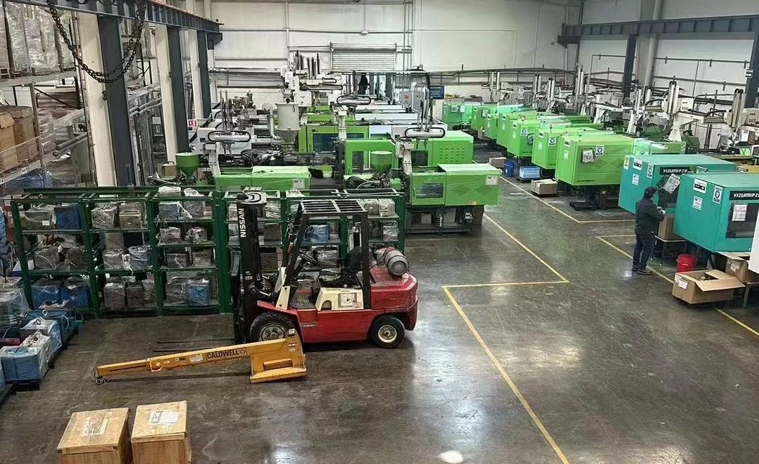 Tutamen Tijuana Plant 01 — injection-molding press row with green-housed Toshiba and Welltec machines